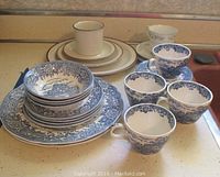 Grouped photo of all china pieces including plates, bowls, cups, and saucers with the English Village blue and white design