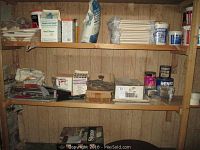 Shelves with various tiling supplies including tile cutter, adhesive tubs, boxes, and bags.