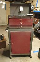 Red and silver metal toolbox with three drawers on a wheeled cabinet base