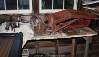 Assortment of grease guns, old toolbox and hand tools on a garage workbench under a window.