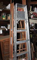 Photo of two A-frame ladders stacked side by side including wood and aluminum models.