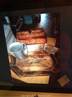 Wooden serving tray with engraved floral design, pewter mug sitting inside, and Bombay Co box in background.
