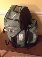 Green and black carrying bag with logo and straps on table.