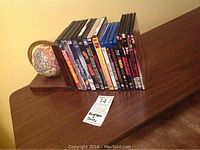 Photo showing assortment of DVD and BluRay cases arranged upright between bookends, some visible titles and cases are identifiable.