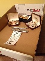 Photo showing cuff links in cases, CN Rail pins, and two metal bottle openers on cardboard box