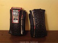 Front view of two folded Kenda Honey BadgerPro mountain bike tires with label showing size and tread type.