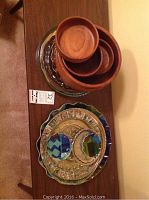 Photo of wooden salad bowls nested on top of several glass and plastic serving trays on a wood surface.
