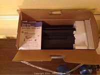 Epson CX8400 printer in box with user guide on top and protective foam.