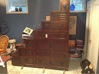 Full view of large wooden Asian step box showing tiers with drawers and doors, along with base frame.