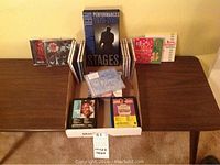 Full view of CDs and eight tracks arranged in a box on a wooden table including the Neil Diamond box set, Christmas CDs and others.