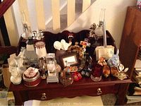 Full overview of wooden table with assortment of decorative items including oil lamps, ceramic bunny, miniature lighthouse, small framed pictures, candle holders and wooden clogs