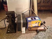 Side view of Keystone R-8 projector next to box of light bulbs and small wooden lamp fixture.