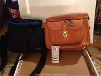 Photo showing two camera bags, one brown leather and one black fabric, placed inside a cardboard box.