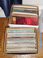 Top view showing two cardboard boxes full of vinyl records with various album covers visible