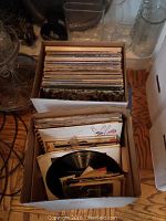 Two cardboard boxes filled with a variety of vinyl records seen from above.