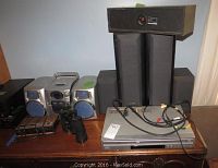 Wide view of all items on a wooden shelf including speakers, stereo, DVD/VHS player and binoculars