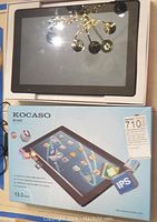 Kocaso M1400 tablet powered on displayed on top of the original product box showing front screen and reflectiveness indicating touchscreen.