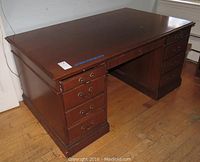 Angled view of the large wooden partner desk showing drawers and side panels.