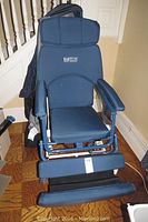 Front view of blue vinyl seat, backrest, armrests, footrests and casters