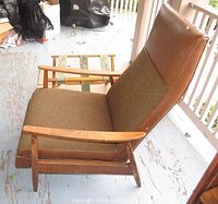 Side view of the recliner chair showing wooden armrests, brown vinyl and fabric upholstery, and the luggage rack behind it.