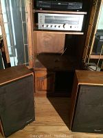 Photo showing Toshiba DVD player on top of Realistic stereo receiver inside a wooden cabinet with two large floor-standing speakers in front of the cabinet.