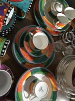 Photo showing multiple pieces of Mikasa Ultima HK 231 dinnerware, including mugs, saucers, dinner plates, rimmed bowls, and serving items with colorful geometric patterns