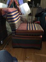 Photo of one striped upholstered chair showing fabric wear and needed recovering. Pattern includes horizontal multi-colored stripes.