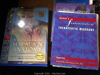 Photo of three anatomy and massage therapy books, including New Atlas of Human Anatomy and Mosby's Fundamentals of Therapeutic Massage.