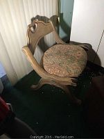 Photo of an antique wooden chair with faded patterned upholstered seat and worn wood finish.