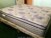 Photo of queen size mattress with purple floral cover placed on mismatched box springs and metal frame.