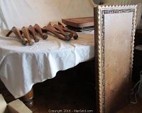 Two wooden table tops with detached legs placed on a covered surface, showing carved edges and disassembled state.