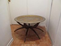 Full view of table showing brass top and six-leg wooden collapsible base
