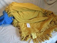 Gold chenille bed cover folded on a bed, showing full texture and fringe edges.