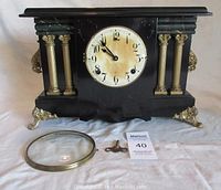 Front view of the Wm. L. Gilbert mantel clock with the glass face cover detached and winding key in front.