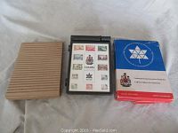 Photo showing the original blue and red stamp box for Canada Centennial stamps, black holder, and a cardboard box sleeve.