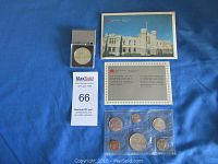 Photo showing uncirculated Canadian coin set sealed in plastic with six coins, a postcard, and certificate card on blue background.