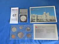 Photo of the 1987 Canadian Mint uncirculated coin set including six coins displayed in a plastic sealed pouch, plus a separate silver dollar coin in hard plastic holder, accompanied by Royal Canadian Mint informational cards.