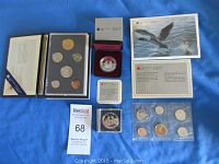 Four coin sets laid out on blue background including uncirculated set, specimen set, proof silver dollar in display box and brilliant uncirculated silver dollar in plastic sleeve.