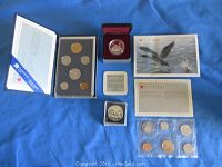 Photo showing all coin sets and individual coins arranged on blue fabric including uncirculated set, specimen set, proof and brilliant uncirculated silver dollars, certificates, and commemorative cards.