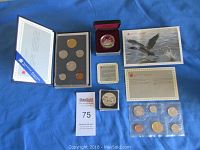 Full lot overview showing four coin sets, individual coin cases, certificates, and a collectible postcard.