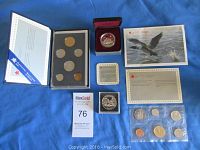 Photo of the four 1989 Canadian coin sets and commemorative silver dollars with original packaging and certificates, arranged on blue fabric background.