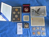 Showing all coin sets and silver dollars including the uncirculated set in display holder, proof silver dollar in presentation case, specimen set in protective sleeve, and paperwork including certificates and informational cards.