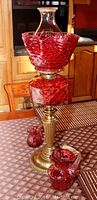 Full view of the cranberry glass oil lamp on brass base with two pitchers.