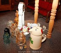 Photo showing ceramic cat clock, glass insulators, ceramic stein, decorative flowers, and bottle openers on table.