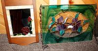 Two stained glass art items: a stained glass hanger with purple flowers and leaves, and a wood-framed mirror with red rose stained glass design.