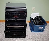 Full view of stacked stereo components beside blue tote bin