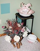 Full lot including ceramic wash bowl, pitcher, white pot, artificial floral arrangement in wooden wheelbarrow, small black wooden table