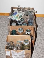 Four wooden crates filled with vintage canning jars and milk bottles, stacked vertically with bottle book on top.