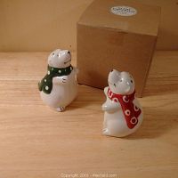 Two ceramic polar bear salt and pepper shakers with scarves facing each other and their original box behind them.