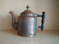 Side view of antique copper and brass coffee pot showing patina, wooden handle with brass fittings, and decorative lid.